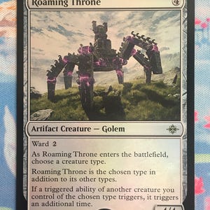 Puede incluir: Una carta coleccionable de Magic: The Gathering titulada Roaming Throne, una criatura artefacto gólem. La ilustración muestra una gran estructura de piedra oscura de múltiples patas con energía púrpura brillante en un paisaje herboso.
