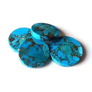Könnte beinhalten: Vier runde türkisfarbene Edelstein-Cabochons mit braunen Adern. Die polierten Steine haben eine leuchtend blaue Farbe und sind auf einem weißen Hintergrund gestapelt. Die Edelsteine werden wahrscheinlich für die Schmuckherstellung verwendet.