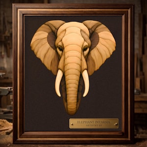 Puede incluir: Una pieza de arte mural de madera con incrustaciones enmarcada que muestra una cabeza de elefante detallada con orejas grandes, trompa y colmillos de color marfil. La obra está sobre un fondo oscuro e incluye una placa de latón ELEPHANT INTARSIA. ARTISTRY BY.