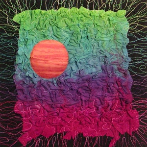 May include: A colorful abstract art quilt with a large, round, orange and pink circle in the center. The quilt is made of fabric that has been gathered and sewn together to create a textured surface. The background is black with white stitching.