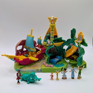 May include: A multi-piece plastic playset featuring a pink and yellow pirate ship with blue sails, a green treehouse structure with a yellow slide, and a blue bed. Includes six small character figurines, a green crocodile, and a pirate figure.