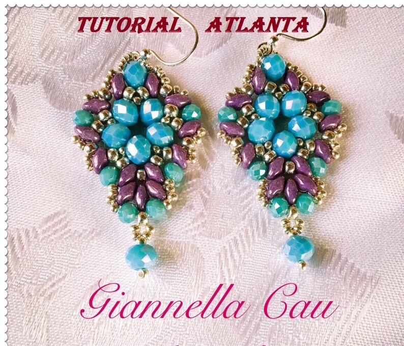 May include: A pair of turquoise, purple, and gold beaded earrings with a teardrop design. The earrings are labeled "Tutorial Atlanta" and "Giannella Cau".