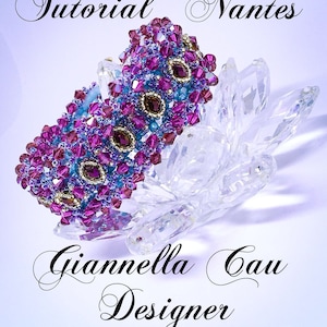 Peut inclure: Un bracelet en perles de couleur violette et bleue avec des accents dorés. Le bracelet est posé sur une surface en cristal transparent. Le texte "Tutorial "Nantes" Giannella Gau Designer" est visible sous le bracelet.