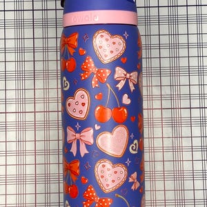 A colorful, patterned water bottle with various heart and bow designs on it.