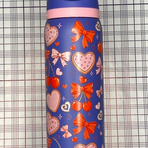 A colorful, patterned water bottle with various heart and bow designs on it.