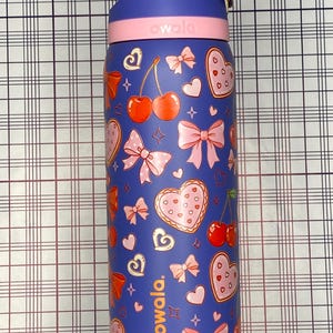 A colorful, patterned water bottle with various cartoon-style illustrations, including hearts, bows, and cherries, on a checkered background.