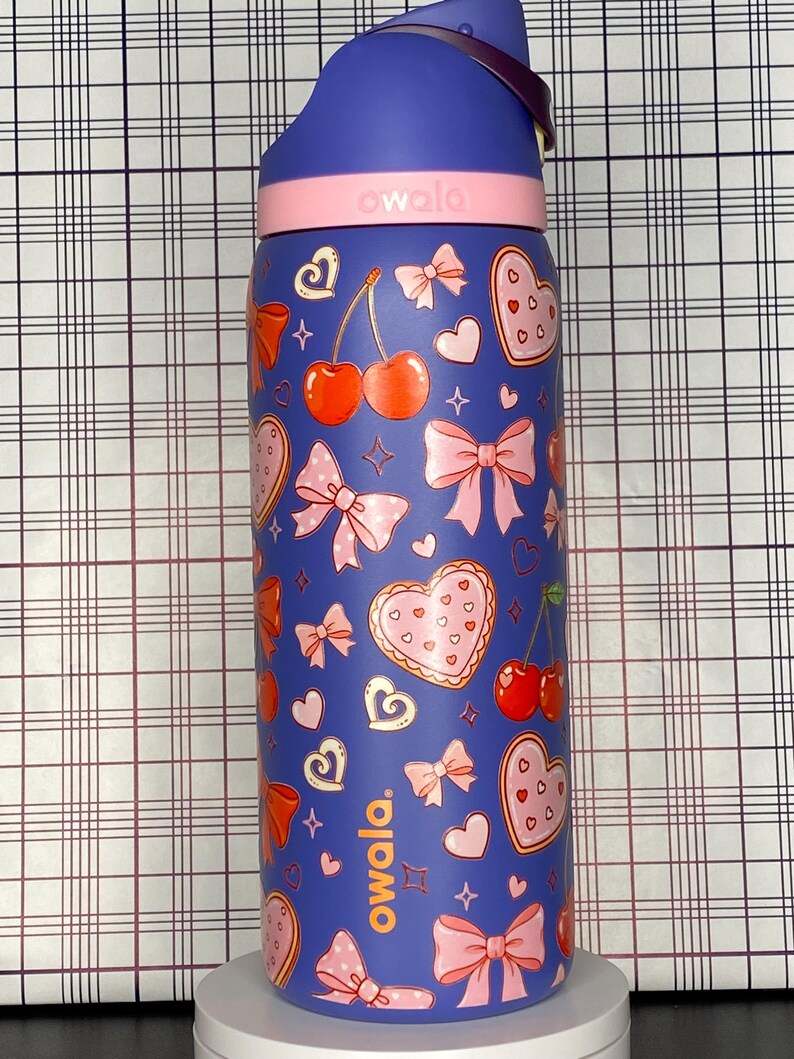 A colorful, patterned water bottle with various cartoon-style illustrations, including hearts, bows, and cherries, on a checkered background.