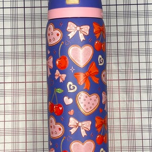 A colorful, patterned water bottle with a variety of heart and bow designs.