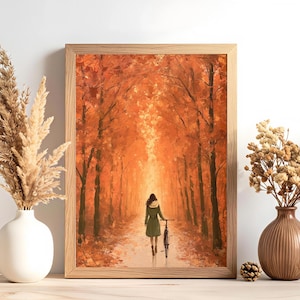 Könnte beinhalten: Ein gerahmter Kunstdruck, der eine Person mit einem Fahrrad auf einem von leuchtend orangefarbenen Herbstbäumen gesäumten Weg zeigt. Das Bild wird von einer weißen Vase mit trockenem Gras und einer braunen Vase mit Blumen flankiert.
