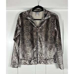 May include: A full-zip jacket with a snakeskin pattern in shades of gray, brown, and black. The jacket has a high collar and is hanging on a black hanger against a white background. The jacket is a medium weight.