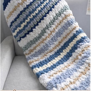 May include: A handmade chunky knit lap blanket in shades of blue, white, and tan. The blanket features a striped pattern and is made of thick, textured yarn. The text "Ready to Ship" is visible in the upper right corner.