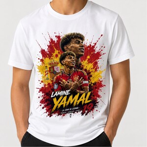May include: A white t-shirt featuring a graphic print of soccer player Lamine Yamal in a red jersey, set against a red and yellow paint splatter background with the Spanish coat of arms, the text LAMINE YAMAL, the number 19, and smaller text.