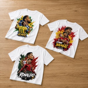 May include: Three white short-sleeve t-shirts featuring graphic prints of soccer players. One shirt shows Neymar with Brazil colors, one shows Lamine Yamal with Spain colors, and one shows Cristiano Ronaldo with Portugal colors and text.