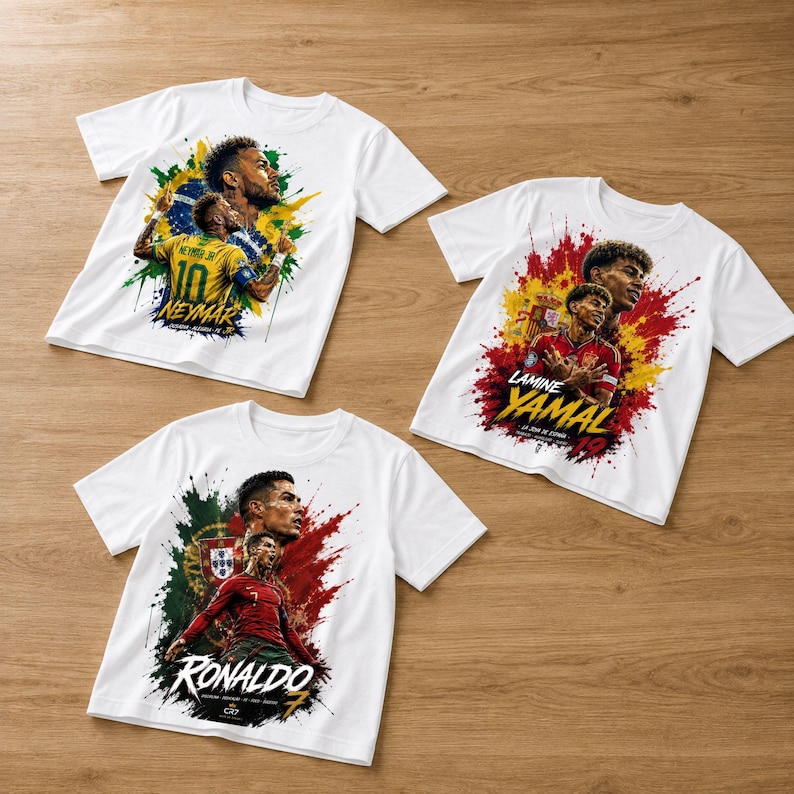 May include: Three white short-sleeve t-shirts featuring graphic prints of soccer players. One shirt shows Neymar with Brazil colors, one shows Lamine Yamal with Spain colors, and one shows Cristiano Ronaldo with Portugal colors and text.