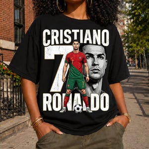 May include: A black t-shirt featuring a graphic print of Cristiano Ronaldo in a red and green soccer uniform. The design includes the text CRISTIANO RONALDO in large white letters, a large number 7, and a soccer ball at the bottom of the graphic.