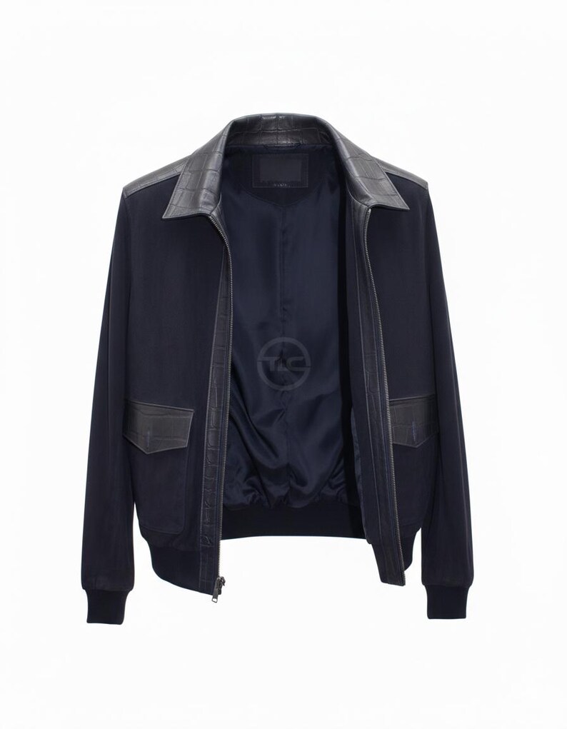 May include: A navy blue bomber jacket with a black leather collar and pocket detailing. The jacket has a zip closure and ribbed hem and cuffs. The interior lining is navy blue with a logo.