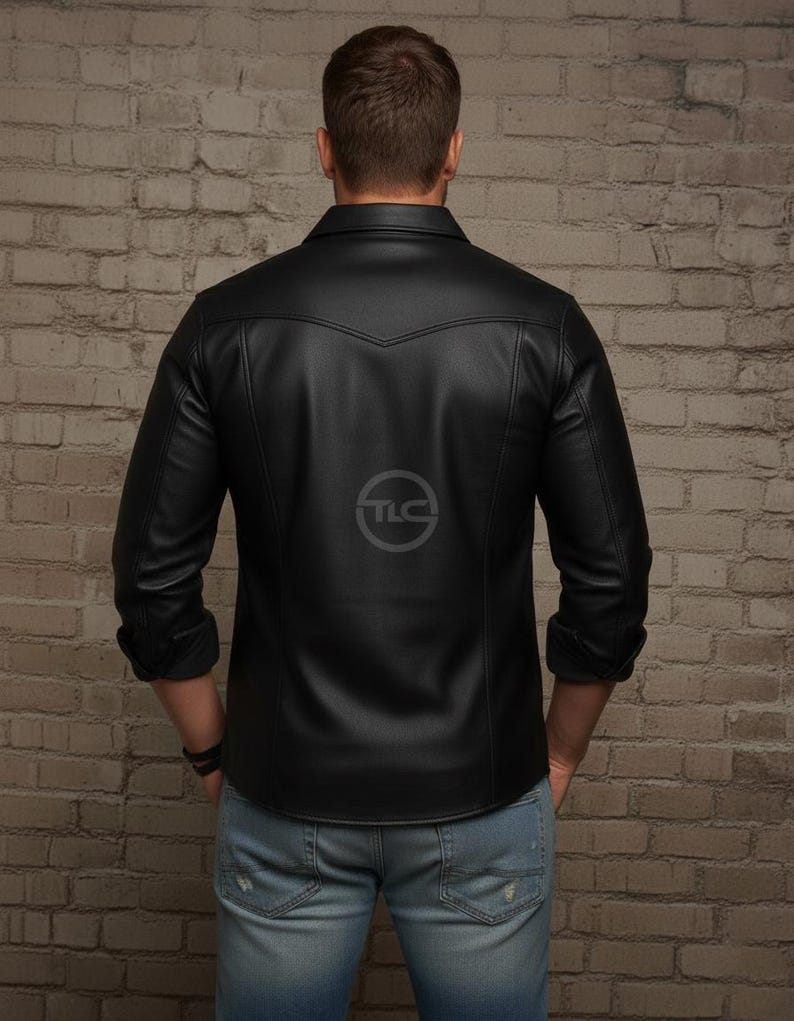 Puede incluir: Camisa de cuero negra con cuello cl&aacute;sico y mangas largas. La camisa presenta un detalle de canes&uacute; en la espalda y un logotipo sutil. Las mangas est&aacute;n dobladas. El modelo lleva vaqueros azules.