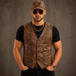 Puede incluir: Un chaleco de cuero marrón con estampado de piel de serpiente y gorra a juego. El chaleco tiene botones y un corte clásico. La persona lleva una camiseta negra, una cadena de oro, un reloj y gafas de sol. El conjunto es elegante y atrevido.