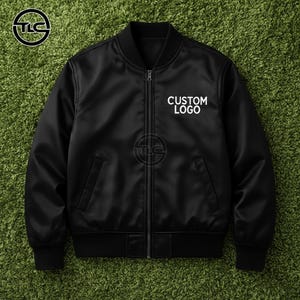 May include: Black bomber jacket with a zipper closure, two front pockets, and a ribbed collar and cuffs. The jacket features the text "CUSTOM LOGO" in white on the chest. The jacket is displayed on a green surface.