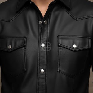 Puede incluir: Camisa negra con botones, dos bolsillos en el pecho y cuello cl&aacute;sico. La camisa tiene botones plateados y una superficie texturizada y perforada. El dise&ntilde;o incluye costuras decorativas a lo largo del canes&uacute; y los bordes de los bolsillos.