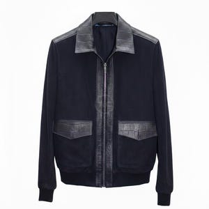 May include: A navy blue bomber jacket with black leather detailing. The jacket has a black leather collar, a zip closure, and two front pockets with leather detailing. The cuffs and hem are ribbed.