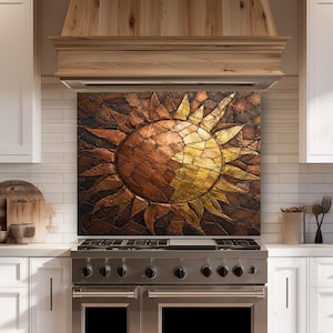 May include: A rectangular kitchen backsplash panel featuring a mosaic-style sun design. The sun is composed of textured, overlapping pieces in shades of metallic gold, bronze, and dark brown, creating a radiant, multi-dimensional sunburst pattern.
