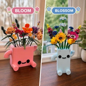 以下が含まれることがあります： 漫画のような顔と腕が付いた2つの長方形のプランター。BLOOMとラベル付けされたピンクのプランターにはカラフルなプラスチック製の花束が入っています。BLOSSOMとラベル付けされた水色のプランターには、様々なプラスチック製の花が鮮やかにアレンジされています。