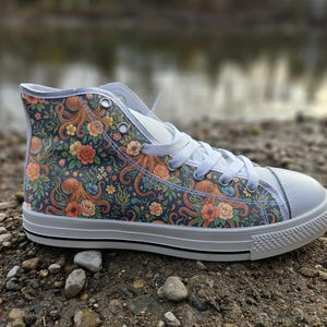 May include: A high-top trainer featuring a dark blue canvas upper with a repeating pattern of orange octopuses, pink flowers, and green foliage. The shoe includes white laces, a white rubber toe cap, and a white sole with a thin black stripe.