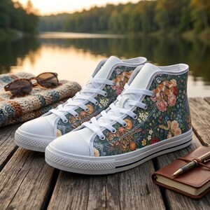 May include: A pair of high-top trainers featuring a dark teal canvas upper with a repeating pattern of coiled snakes, orange and pink roses, and small white flowers. The shoes have white laces, white rubber toe caps, and white rubber soles.