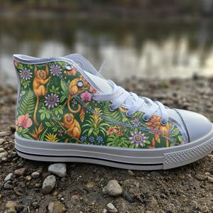 May include: A high-top trainer featuring a vibrant green jungle print with golden monkeys, purple passion flowers, and tropical foliage. The shoe has white laces, a white rubber toe cap, and a white sole with a thin black stripe along the side.