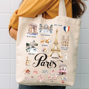 May include: Beige tote bag featuring illustrations of Parisian landmarks, including the Eiffel Tower, Arc de Triomphe, and Notre Dame Cathedral. The word "Paris" is written in elegant script, with "France" below.