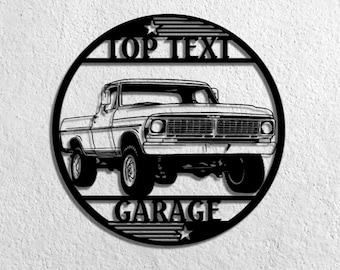 Op de afbeelding: Zwarte metalen wandkunst met een klassiek pick-up truck ontwerp. De truck is gecentreerd in een cirkelvormige lijst, met de woorden "TOP TEXT" en "GARAGE" boven en onder de truck. Het ontwerp bevat sterren en horizontale lijnen.
