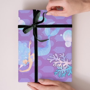 Può includere: Carta da regalo viola con un'illustrazione di sirena, coralli e bolle. È legata con un nastro di velluto nero. Il testo in basso recita: DIGITAL DOWNLOAD ONLY; MOCKUPS ARE FOR ILLUSTRATION; COLORS MAY VARY; OPTIONAL: USE INCLUDED ZAZZLE LINK FORPRINTING.