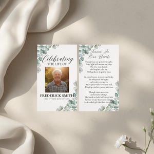 May include: A memorial card featuring a photograph of Frederick Smith, adorned with eucalyptus foliage. The left panel reads "Celebrating the Life of" with his name and dates. The right panel displays a poem titled "Forever In Our Hearts."