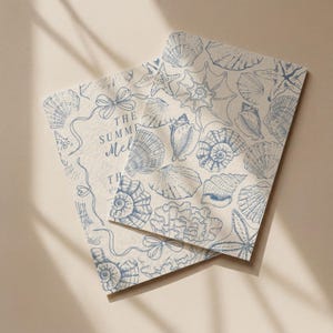 May include: Two rectangular cards with a beige background and a blue seashell pattern. The cards have a variety of seashells, starfish, and coral illustrations. The text "THE SUMMER Mel" is visible on one card.