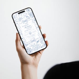 May include: A smartphone displays a blue and white invitation with seashell illustrations. The text reads "The Summer Melissa Turned Thirteen." The phone is held in a person's hand against a white background. The invitation includes event details.