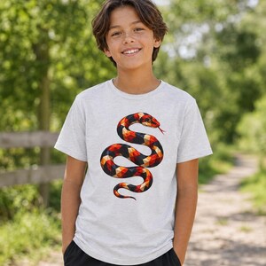 Könnte beinhalten: Ein hellgrau meliertes Kurzarm-T-Shirt mit einem Grafikdruck einer gewundenen Schlange. Die Schlange besteht aus einem geometrischen Low-Poly-Muster in leuchtenden Rot-, Orange-, Gelb- und Schwarztönen mit einer sichtbaren roten gespaltenen Zunge.
