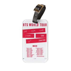 May include: A clear luggage tag with the text "BTS WORLD TOUR" in pink. The tag has a black leather strap with a gold buckle. Red rectangles display names and a checkmark. The bottom of the tag lists tour dates and locations.