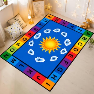 May include: A colorful educational rug with a blue center featuring a yellow sun, white clouds, and numbers. The border displays the alphabet in rainbow colors. A fun and engaging learning tool for children.