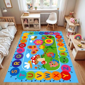 Pode incluir: Um tapete retangular infantil com fundo azul e design colorido. O tapete apresenta uma borda de letras do alfabeto e uma cena central com insetos de desenho animado, flores e um cogumelo. O tapete &eacute; projetado para um quarto infantil.