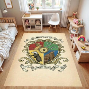 May include: A rectangular beige rug featuring the Hogwarts crest. The crest is divided into four sections, each with a different animal and color. The rug has the words "Hogwarts", "Draco", "Dormiens Nunquam", and "Titillandus" on it.