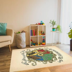 May include: A rectangular beige rug featuring the Hogwarts crest. The crest is a colorful emblem with a shield design, including a lion, eagle, badger, and snake. The rug is placed in a room with a white bookshelf and toys.