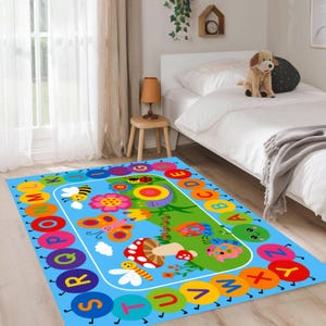 Pode incluir: Um tapete retangular azul para crian&ccedil;as com uma borda de alfabeto colorida. O tapete apresenta um design central com insetos de desenho animado, flores e um cogumelo. As letras do alfabeto est&atilde;o em um arco-&iacute;ris de cores.