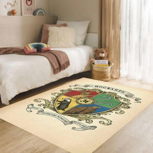 May include: A rectangular rug featuring the Hogwarts crest in a vintage style. The crest is a shield divided into four sections, each with a different animal and color. The rug has a cream-colored background and is placed on a wooden floor.