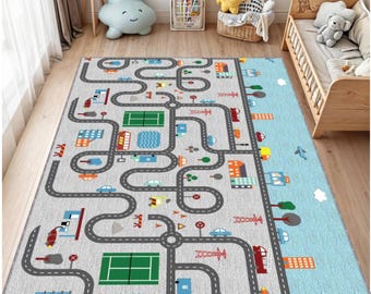 May include: A gray children's play rug with a road map design. The rug features gray roads, buildings, cars, and a tennis court. The right side of the rug is light blue with clouds and airplanes. The rug is designed for a child's bedroom or playroom.