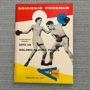 May include: Vintage souvenir program cover with a red and yellow design. The cover features two boxers in action, wearing shorts and gloves. Text includes "Souvenir Program," "Dapper Dan," and "Golden Gloves Finals."