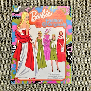 May include: A vintage Barbie paper doll book titled "Fashion Originals" with illustrations of Barbie in various outfits. The cover features a blonde Barbie in a red and white gown, surrounded by colorful floral and psychedelic designs.