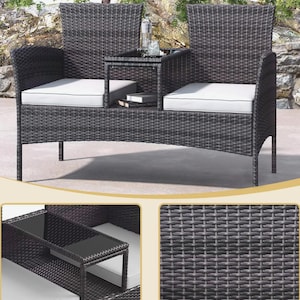 Puede incluir: Un sof&aacute; de exterior de mimbre gris oscuro con una mesa incorporada. El sof&aacute; tiene dos asientos con cojines blancos y una peque&ntilde;a mesa en el medio. Una botella y un vaso est&aacute;n sobre la mesa. El sof&aacute; est&aacute; hecho de mimbre tejido.