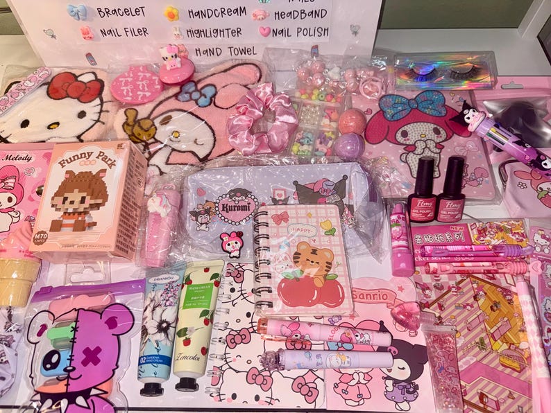 Op de afbeelding: Een verzameling roze en pastelkleurige accessoires en briefpapier, waaronder producten met Hello Kitty- en My Melody-thema's. De afbeelding toont nagellak, handcr&egrave;me, een notitieboek en diverse andere schoonheids- en briefpapierbenodigdheden.