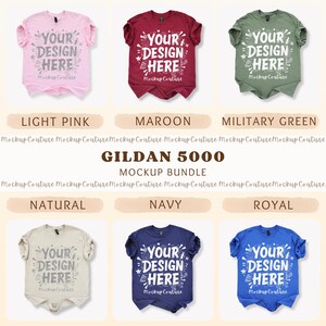 K&ouml;nnte beinhalten: Ein Mockup-Bundle von Gildan 5000 T-Shirts in verschiedenen Farben, darunter Hellrosa, Bordeaux, Milit&auml;rgr&uuml;n, Natur, Marineblau und K&ouml;nigsblau. Jedes Shirt zeigt den Text "YOUR DESIGN HERE" in einer stilisierten Schriftart.
